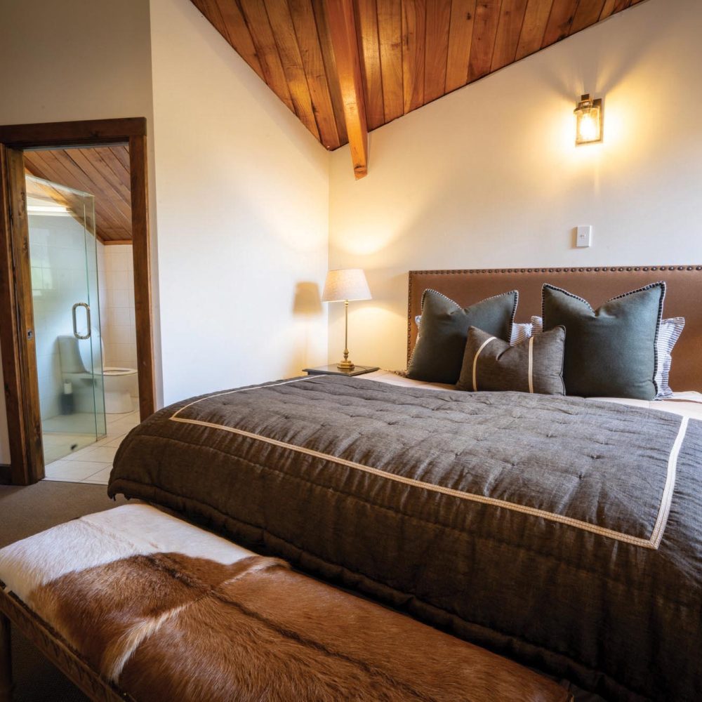 Kuranui Lodge Bedroom and En-Suite Bedroom in Kuranui Lodge with doorway leading to modern en-suite bathroom.